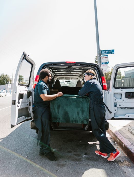 Two movers load a van with furniture during moving day.