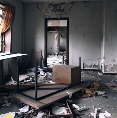 A devastated room showing signs of destruction and neglect, filled with debris and overturned furniture.